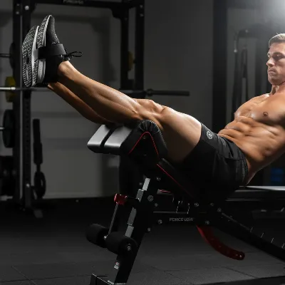 Force USA MyBench with leg developer attachment, focusing on an athlete performing decline leg raises for abdominal strength.